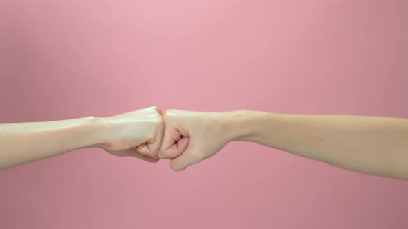 Slow motion of two hand use fist bump on pink background.