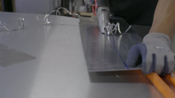 Worker cutting metal sheet in workshop