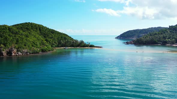 Beautiful coastline of tropical islands with blue azure sea surface reflecting white clouds on brigh