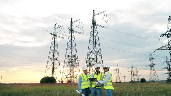 Three Electricians Observing a Massive Power Plant at Sunset