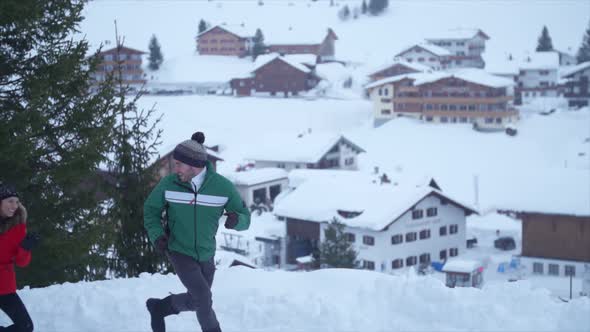 A man and woman couple having a playful snowball fight lifestyle in the snow at a ski resort