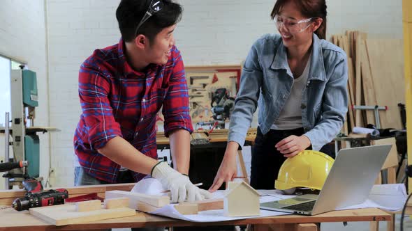 Couple Architect designing wood construction project on drawing paper in workshop