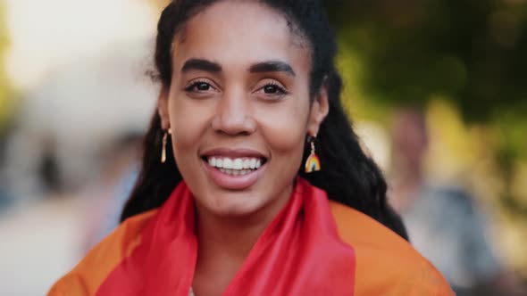 A woman wrapped in colorful flag looking to the camera during pride gay parade