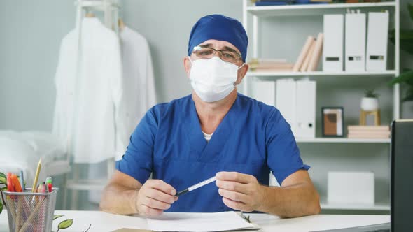 Aged Doctor Wearing Protective Face Mask Medical Uniform Sitting at Workplace Male Therapist Working