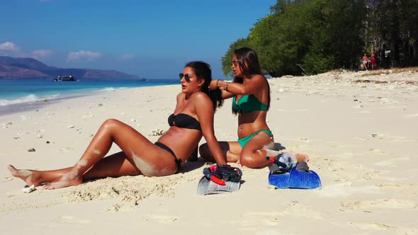 Pretty happy ladies on holiday enjoying life at the beach on summer white sandy and blue background 