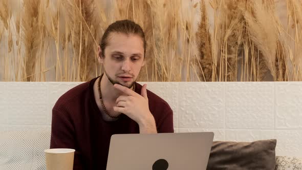 A Young European Man Is Working Online On A New Project and Using A Laptop in A Bright Cafe