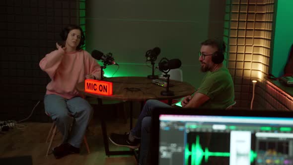 Young podcasters working in dark studio