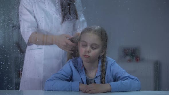 Nanny Braiding Little Girls Hair Behind Rainy Window Care in Orphanage