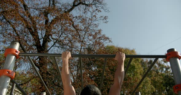 Young Man Is Doing Pull Ups on the Bar in Good Weather 