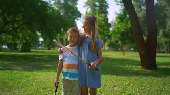 Two Smiling Siblings Posing with Rackets