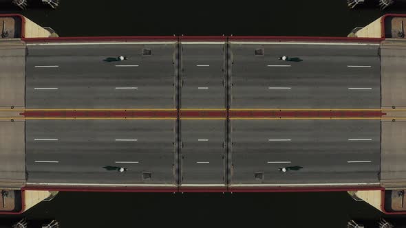 Top Down Ascending Footage of Cars Passing on Bridge Over Water Symmetrical Composition