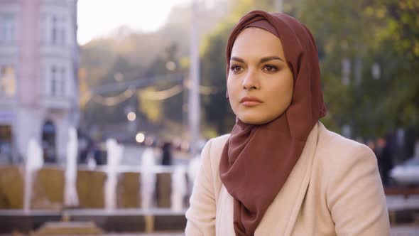 A Young Beautiful Muslim Woman Thinks About Something in a Street in an Urban Area