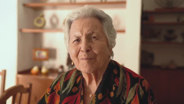 Senior smiling woman in warm shawl in dining room