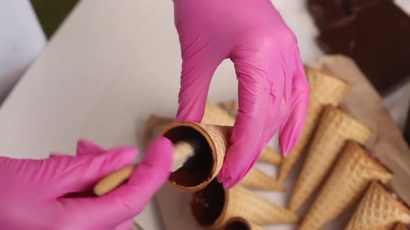 A Woman Smears Waffle Cones With Liquid Chocolate. Puts Them On The Rack.