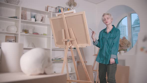 A Young Attractive Woman Artist Drawing a Skull and Other Figures From the Table