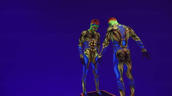 Twins Acrobats In Ultraviolet Luminous Ufo Style Costumes Stand On One Arm