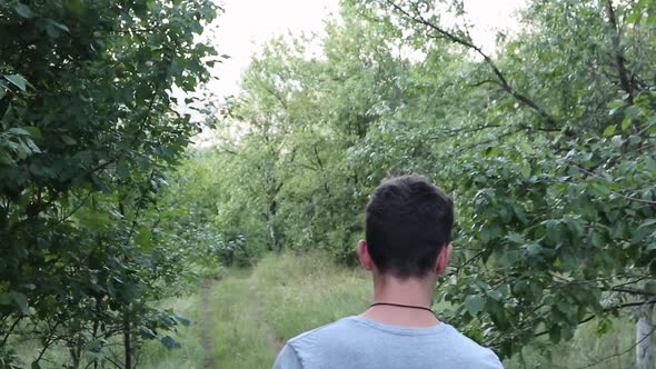 Young Man Walking in The Forest, Summer time. close up shot from the back