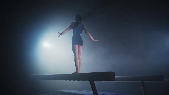 Young Sportswoman on Competition of Artistic Gymnastics Female Gymnast is Performing on Balance Beam