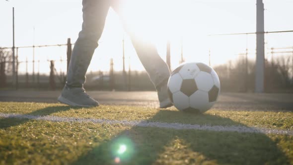 A Child Girl Playing with Soccer Ball Under Sun Light. Green Field in City Park at Sunny Day. Action