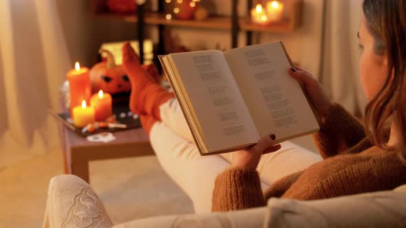 Young Woman Reading Book at Home on Halloween