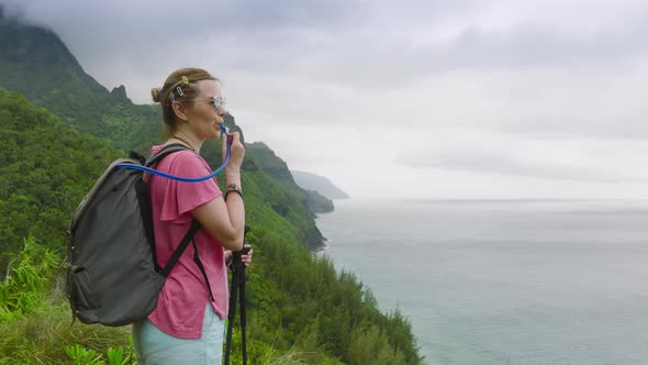 Woman Drinking Water During Hike By Kalalau Trail with Cinematic NaPali Coast