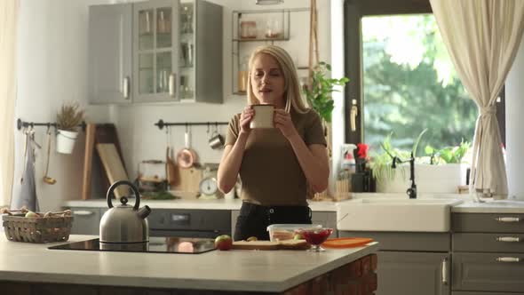 blonde woman in the kitchen with a cup of coffee