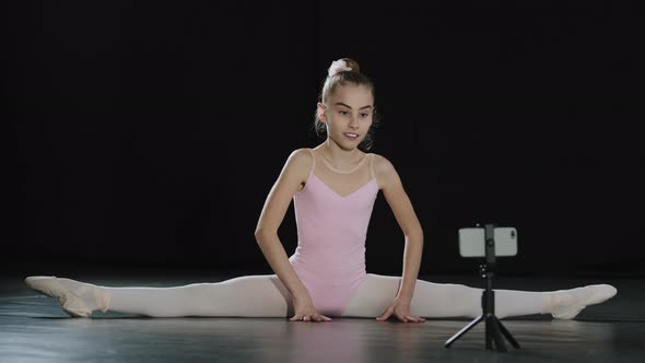 Girl Teenager Child Ballerina Acrobat Gymnast Sits on Floor Dance Class Online Lesson with Internet