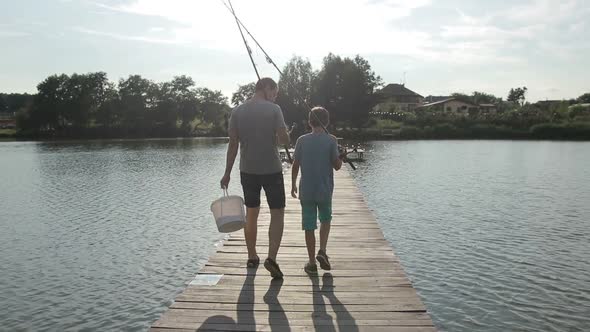 Father and Son Going Fishing with Rods on Lake
