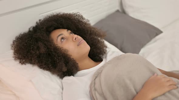 Pensive Young African Woman Laying Awake in Bed