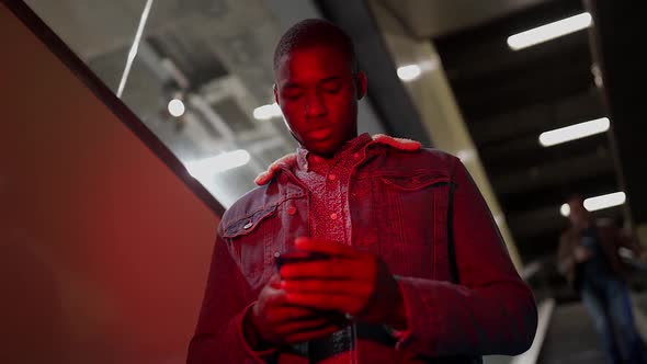 Black man with phone on moving stairs