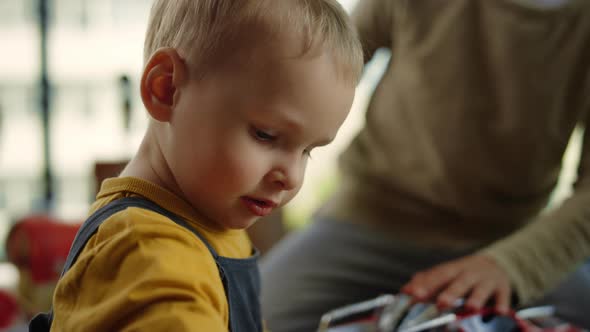 Boy Playing Toy Car Indoors. Elder Brother Hands Grabbing Younger Brother.