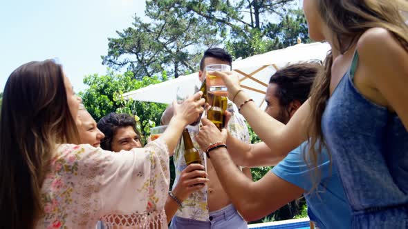 Group of happy friends toasting beer bottles and glasses at outdoors barbecue party