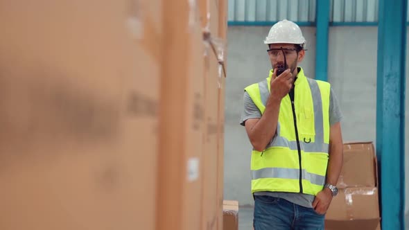 Professional Cargo Worker Talks on Portable Radio to Contact Another Worker