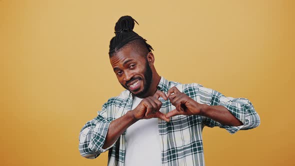 Young Afro American Male Smiling Showing Heart Shaped Hand Gesture and Winking you