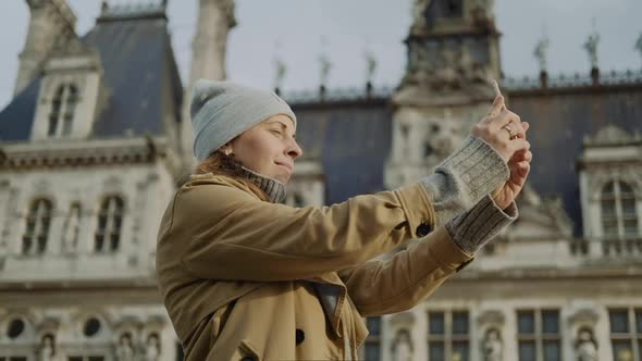 Young woman in a gray hat makes a picture on the phone in Paris in autumn