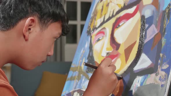 Close Up Side View Of An Asian Artist Boy Holding Paintbrush Mixed Colour And Painting On The Canvas