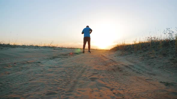 Running Man Silhouette in Sunset Time. Outdoor Cross-country Running. Athletic Young Man Is Running