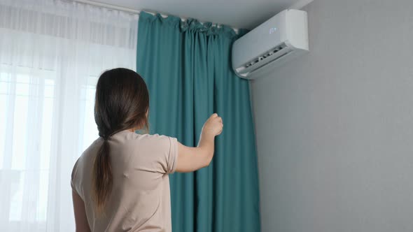 Brunette Woman Turns on the Air Conditioner Back View