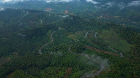 Aerial view over a winding road in the mountains of a tropical forest, Thailand.