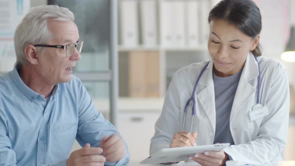 Female Physician Using Tablet and Talking with Senior Male Patient