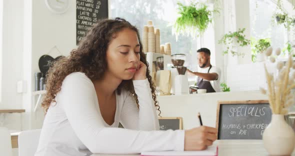 Happy african american male barista making coffee for biracial female client at cafe