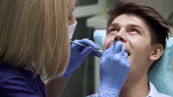 Dentist Examining Teeth with Medical Instruments. Portrait of Man Checking His Teeth. Professional