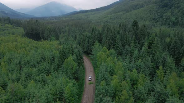 Aerial View of Suv Car Moving By Path Road in Mountains Overcast Misty Rainy Weather