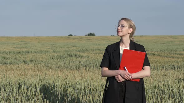 employee of an agricultural firm with notebook checks the quality of wheat in the field