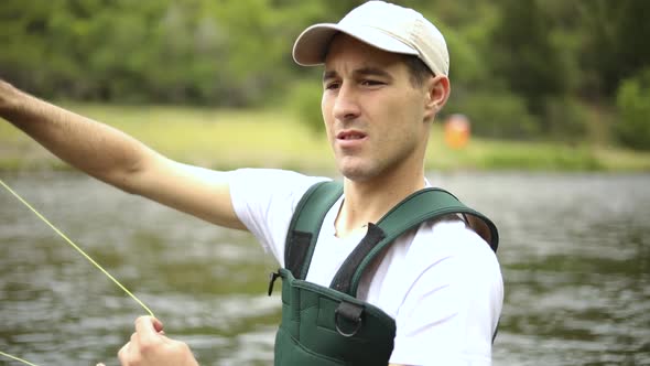 Slow Motion Shot of a Caucasian male fisherman casting his hook while Fly Fishing. He is standing in