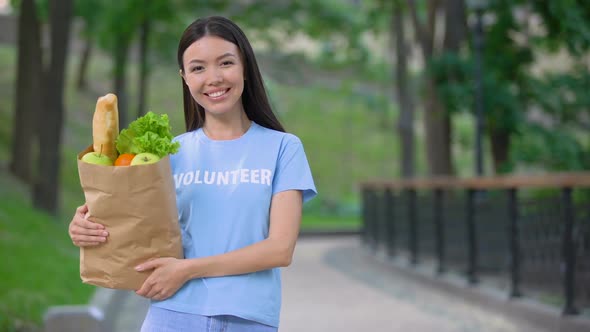 Cheerful Female Volunteer Holding Grocery Bag Outdoors Smiling Camera, Donation