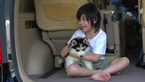 Happy Asian Child And Siberian Husky Puppy Sitting In The Car