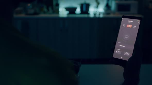 Man Sitting in House with Automation Light System Holding Smartphone