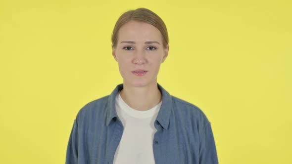 Serious Young Woman Looking at the Camera on Yellow Background