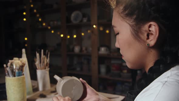 Young Woman Potter Chipping Away the Excess of the Clay From the Bottom of a Cup